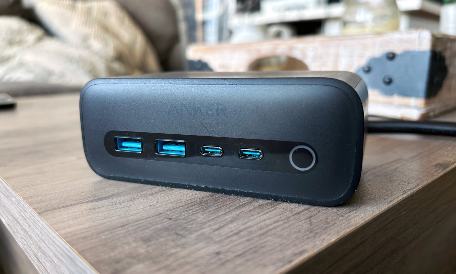 O Anker 525 está localizado no topo de uma mesa de madeira marrom.