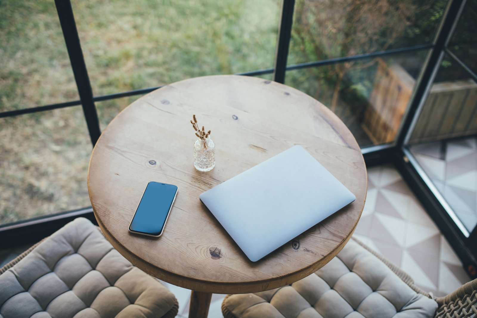 O laptop e o smartphone em uma mesa redonda de madeira em um interior confortável.
